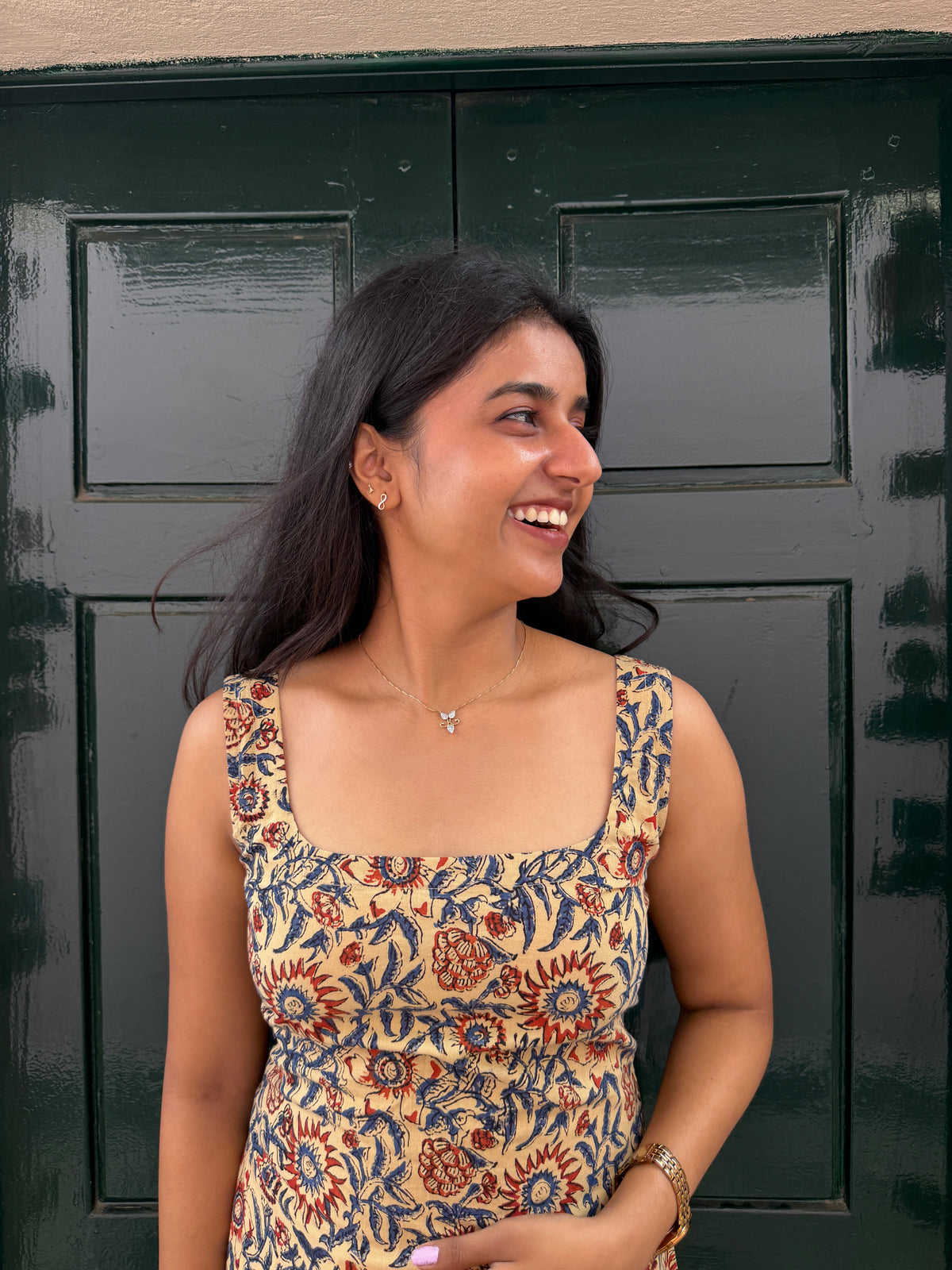 Woman in a patterned dress standing in front of a dark green door