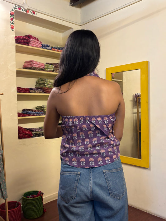 Person wearing a purple floral top and blue jeans standing in front of a mirror.
