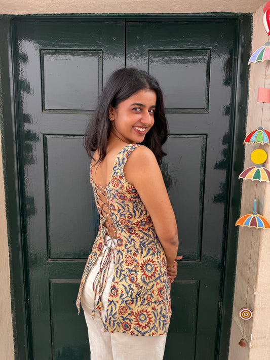 Woman standing in front of a black door with colorful decorations above.