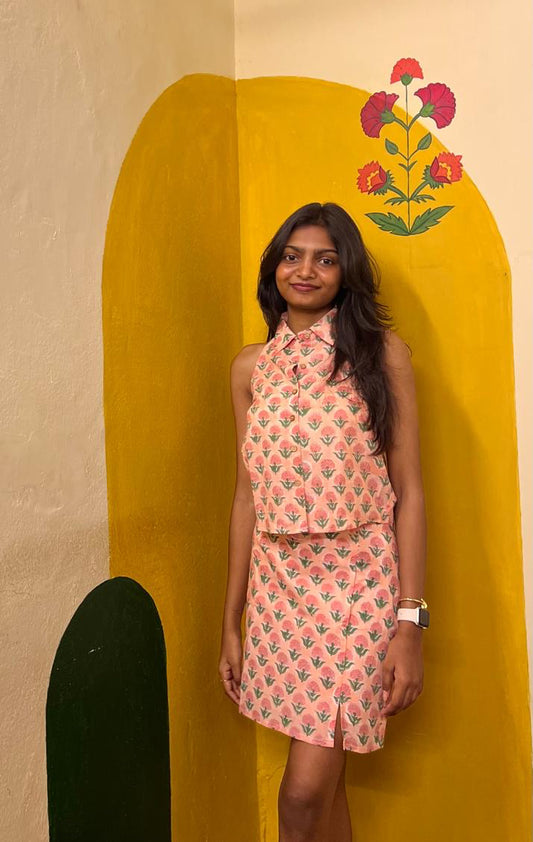 Woman in a patterned dress standing against a colorful wall with floral design