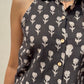 Black halter top with white floral pattern worn by a person against a neutral background