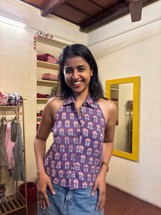Woman in a purple floral top and blue jeans standing in front of a mirror.