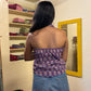Person wearing a purple floral top and blue jeans standing in front of a mirror.