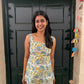 Woman standing in front of a black door with colorful decorations on a wall.