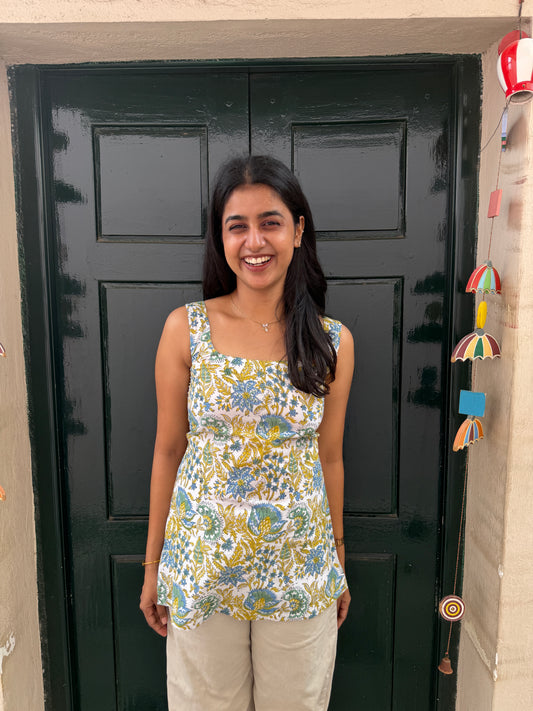 Woman standing in front of a black door with colorful decorations on a wall.