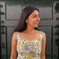 Woman wearing a floral dress standing in front of a dark green door.