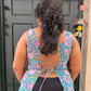 Person wearing a floral top with a back design, standing in front of a green door.