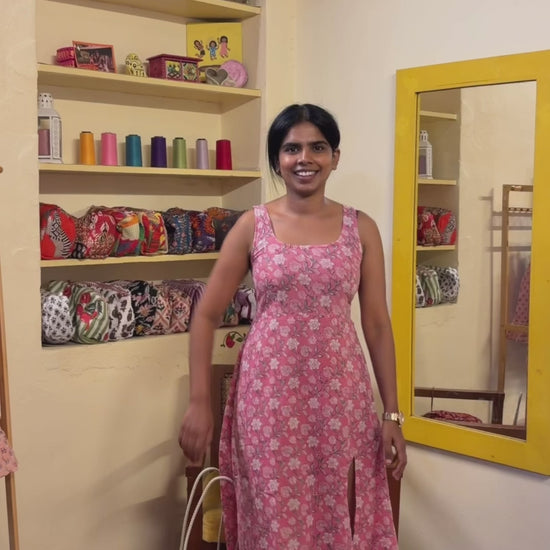 A woman  wearing a sleeveless red V neck floral top and flared skirt with orange and beige flowers. 