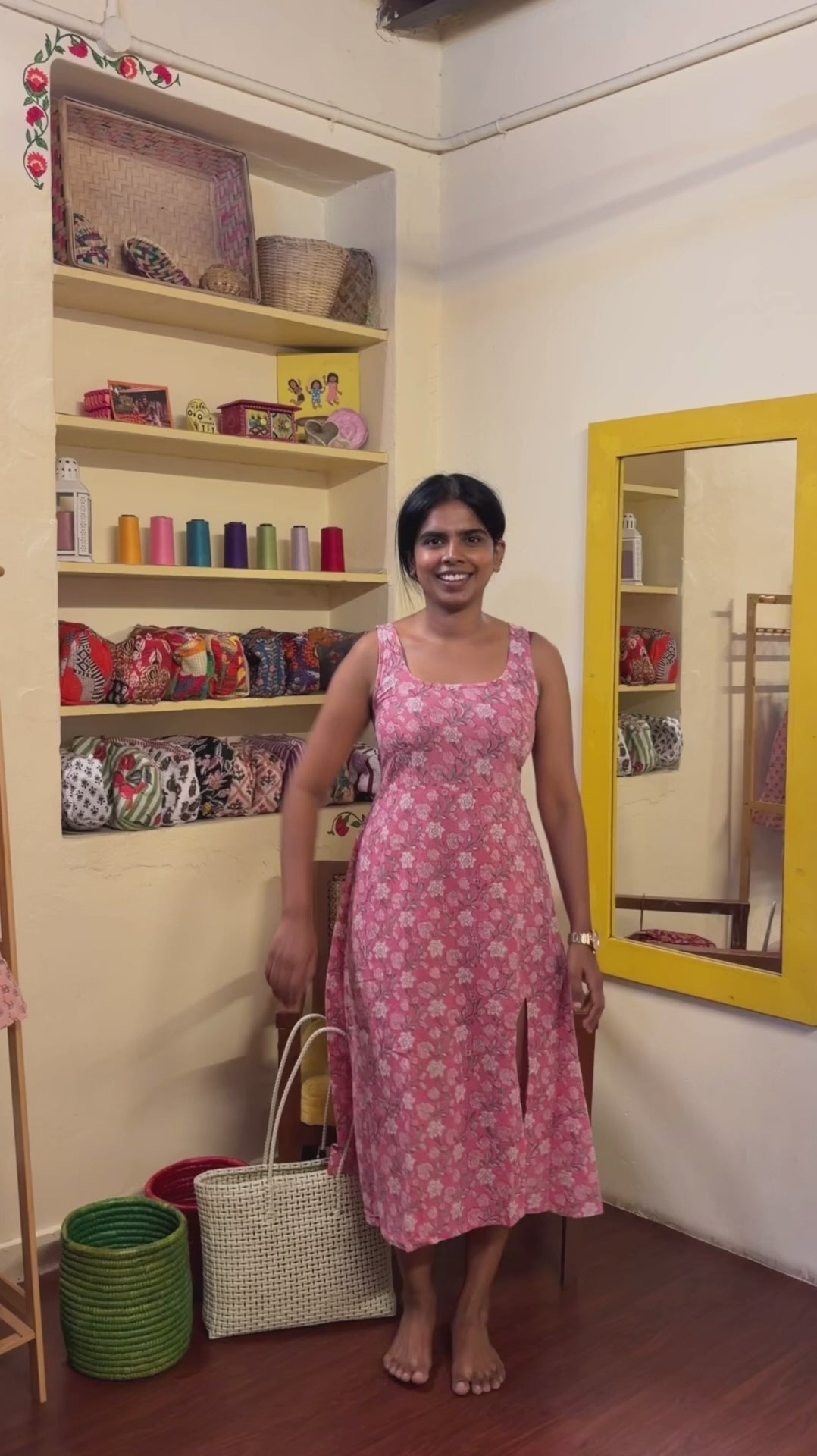 A woman  wearing a sleeveless red V neck floral top and flared skirt with orange and beige flowers. 